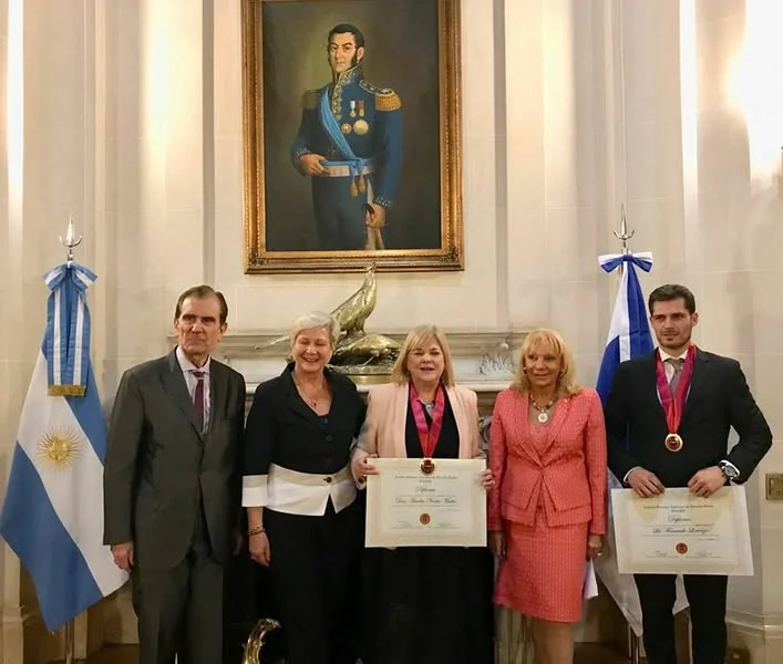 Integrantes distinguidos muestran sus diplomas y medallas junto a las banderas argentinas.