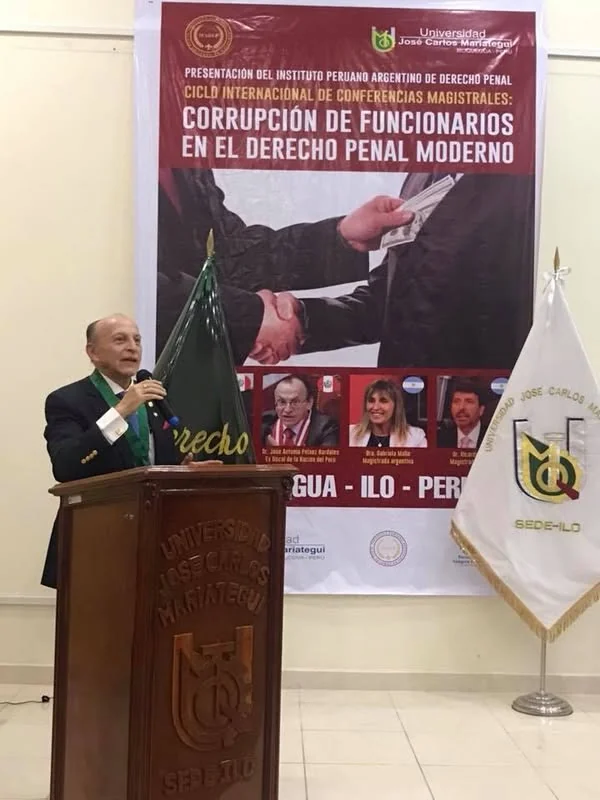 Intervención desde el atril, junto al afiche del ciclo internacional «Corrupción de funcionarios en el Derecho Penal moderno».
