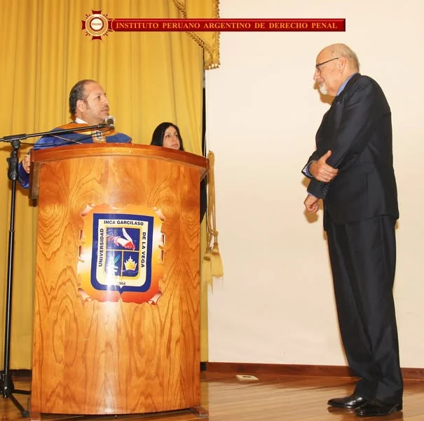 Entrega de una distinción durante la incorporación de juristas, ante el atril de la UIGV.