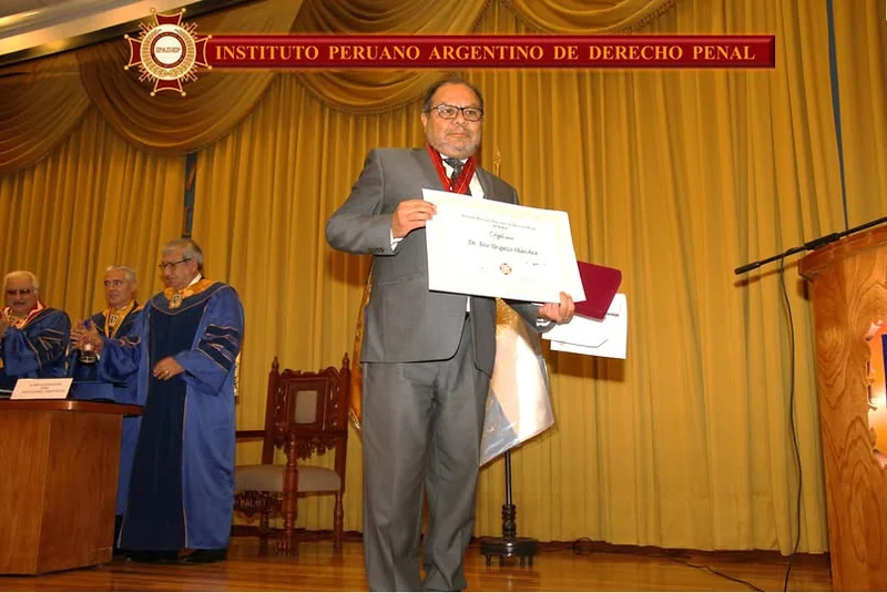 Un distinguido muestra su diploma y medalla ante el público de la ceremonia de la UIGV.