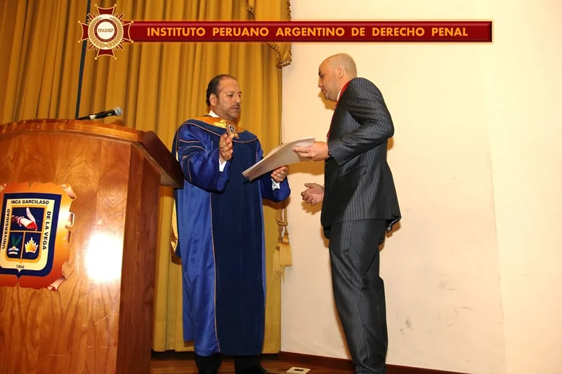 Entrega de un diploma desde el atril durante la ceremonia académica de la UIGV.