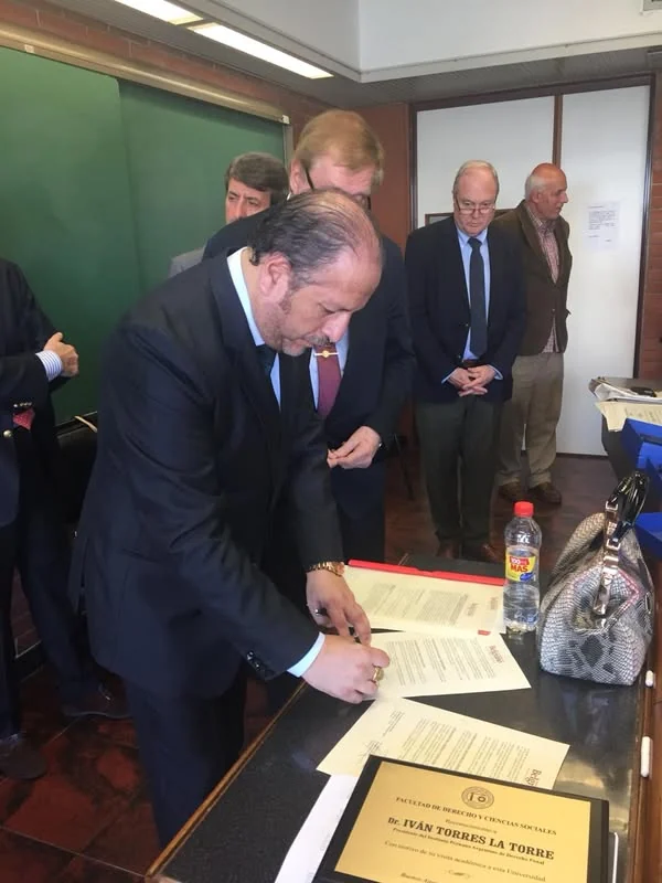 Firma de documentos durante el encuentro de cooperación con la Universidad de Belgrano.