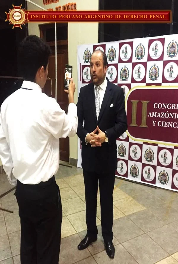 Expositor atendiendo una entrevista con micrófono, ante el panel del encuentro académico de Madre de Dios.