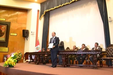 Un participante muestra su diploma ante la mesa de honor de la ceremonia del Colegio de Abogados de Lima.