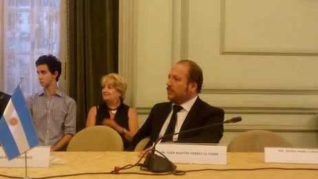 Participantes sentados en la mesa de la ceremonia de la Cancillería, junto a la bandera argentina.