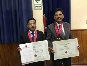 Dos integrantes distinguidos muestran sus diplomas y medallas en la Universidad Privada de Tacna.