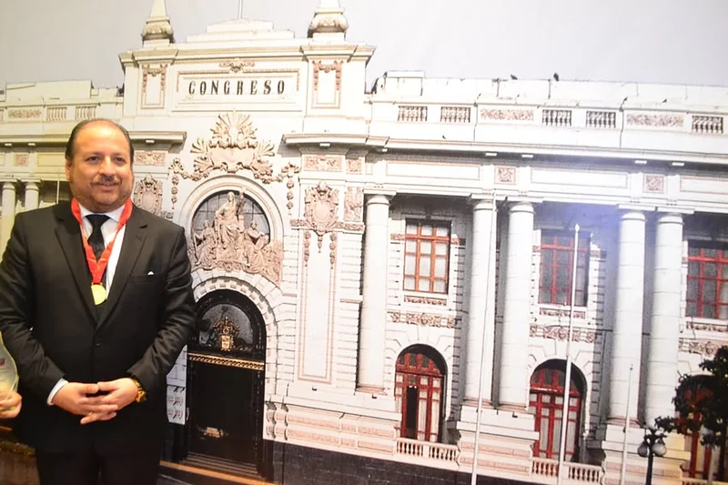 Iván Torres La Torre con su medalla, junto a una imagen del Palacio Legislativo, en el marco de la conferencia sobre lucha contra la corrupción.