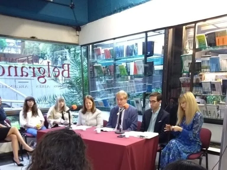 Mesa de participantes durante la conferencia sobre delitos ambientales, en un espacio rodeado de publicaciones jurídicas.