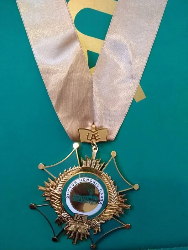 Detalle de la medalla de la Universidad Alva Édison, con cinta blanca.